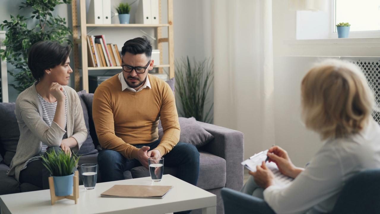 Two partners sitting together with a therapist