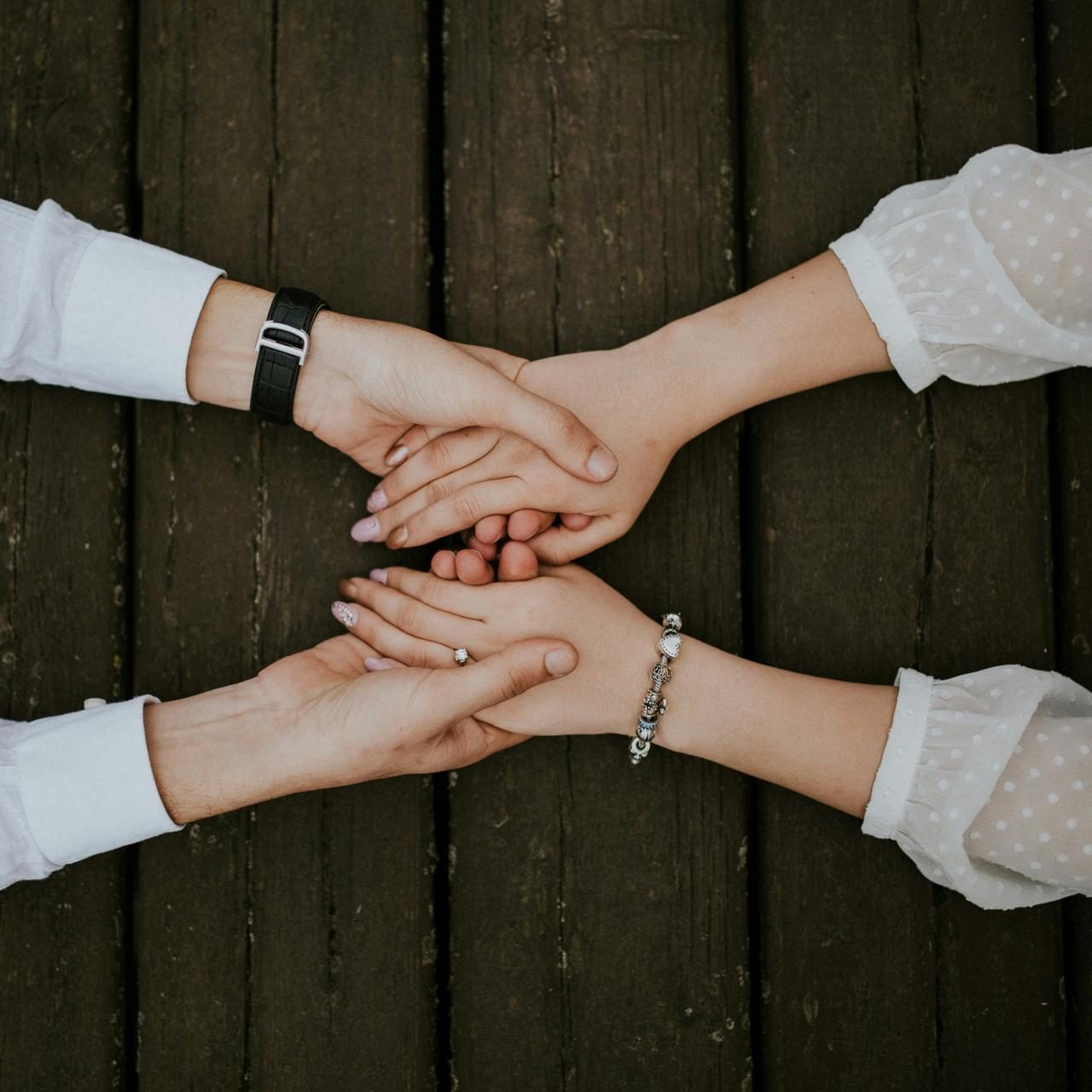 Four hands resting on top of one another