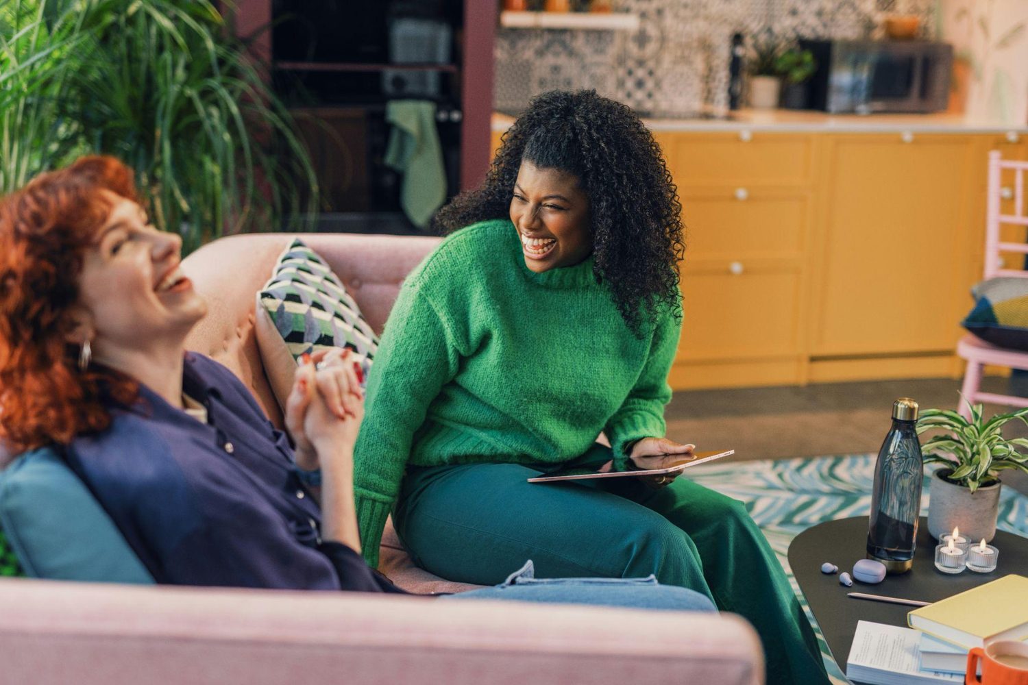 Two people laughing together on a sofa