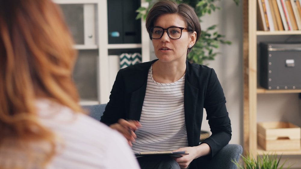 Two people talking on a couch in a bright room