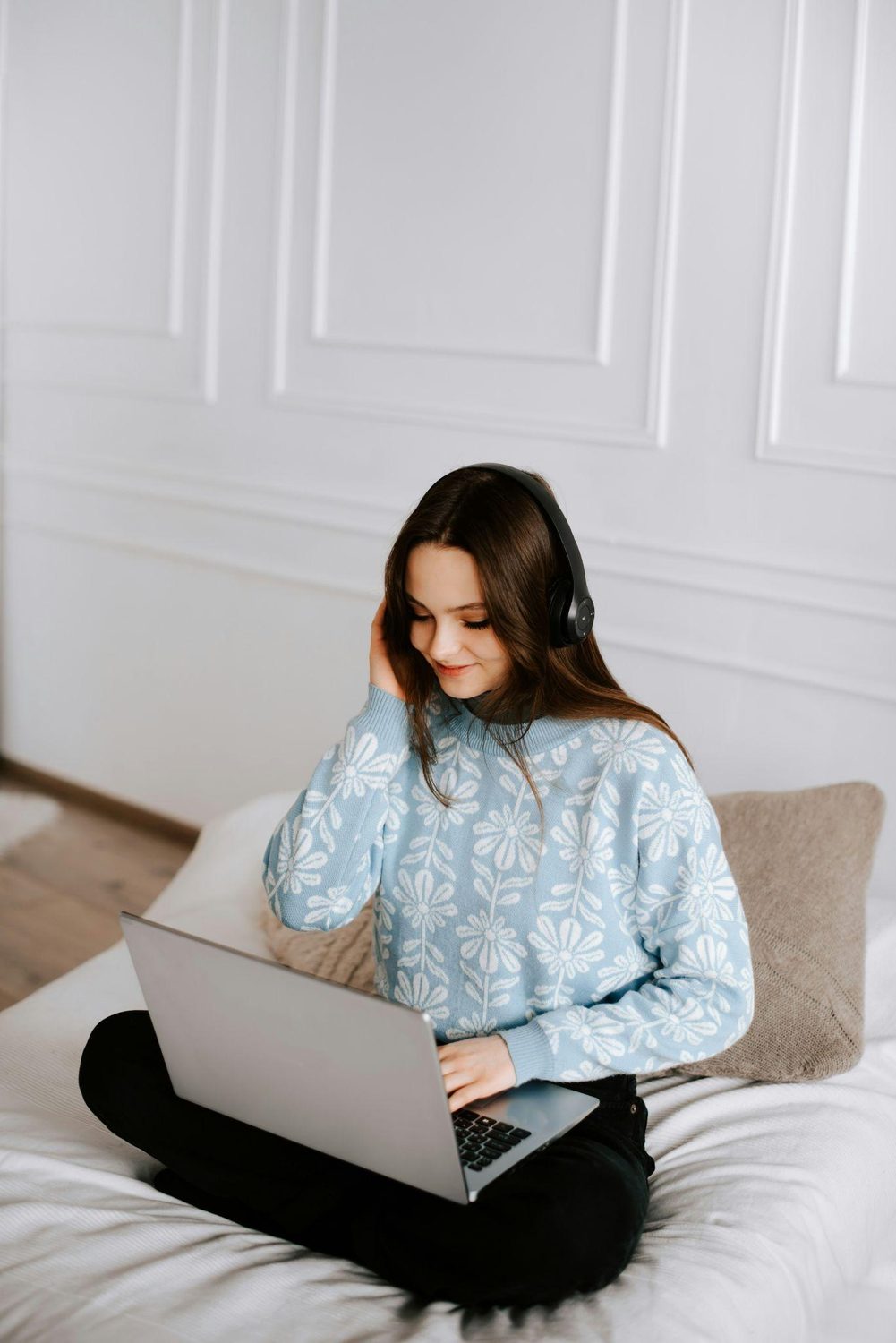 A teenager sitting with a laptop at home
